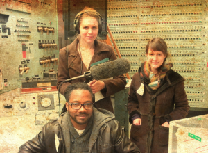 Host Al Letson, producer Tina Antolini, and intern Julie Rawe in the control room of a nuclear reactor in Southeastern Washington State